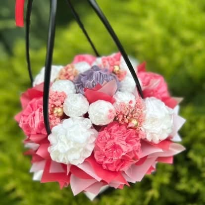 Hanging floral bouquet with pink and white carnations and roses decorated with a decorative heart charm