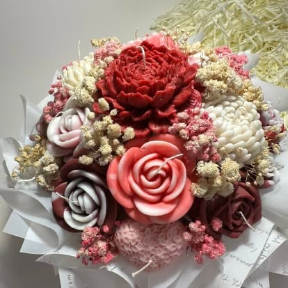 Colorful bouquet of red, pink, and white decorative soap flowers with babys breath filler wrapped in white tissue paper