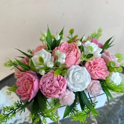 Floral bouquet with pink and white peonies, roses, and green foliage arranged together