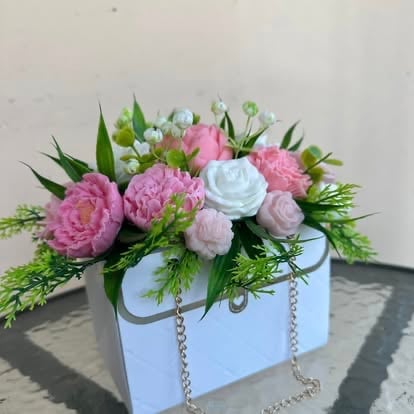 White box floral arrangement with pink carnations, white roses, and green foliage with silver chain handles