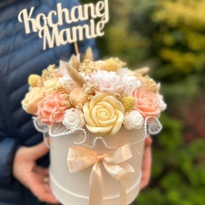 Person holding a white box of peach and cream fabric flowers with a beige ribbon bow and Kochang Mamie branding